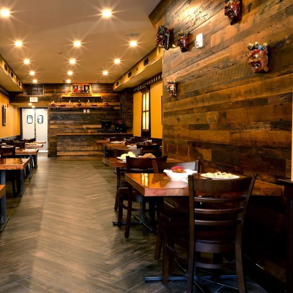 Interior of White Yak restaurant with wooden walls, tables set with food, and decorative masks.